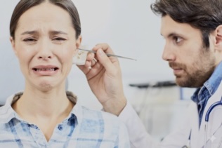 Patient in distress during an ear procedure as a doctor uses a metal instrument at the ear.